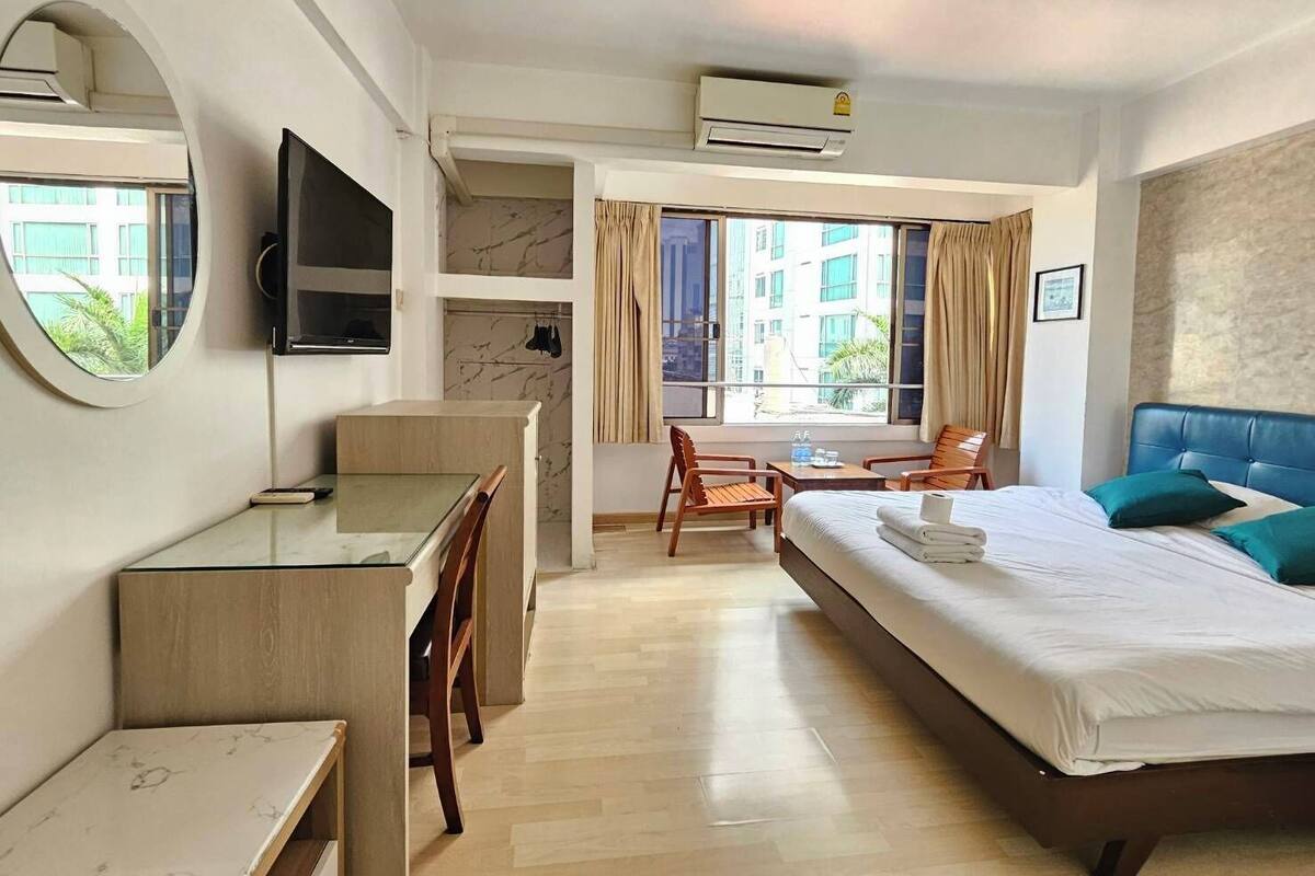 Ein Hotelzimmer mit einem Bett, einem Schreibtisch, einem Stuhl, einem Fernseher und einem Fenster mit Vorhängen.