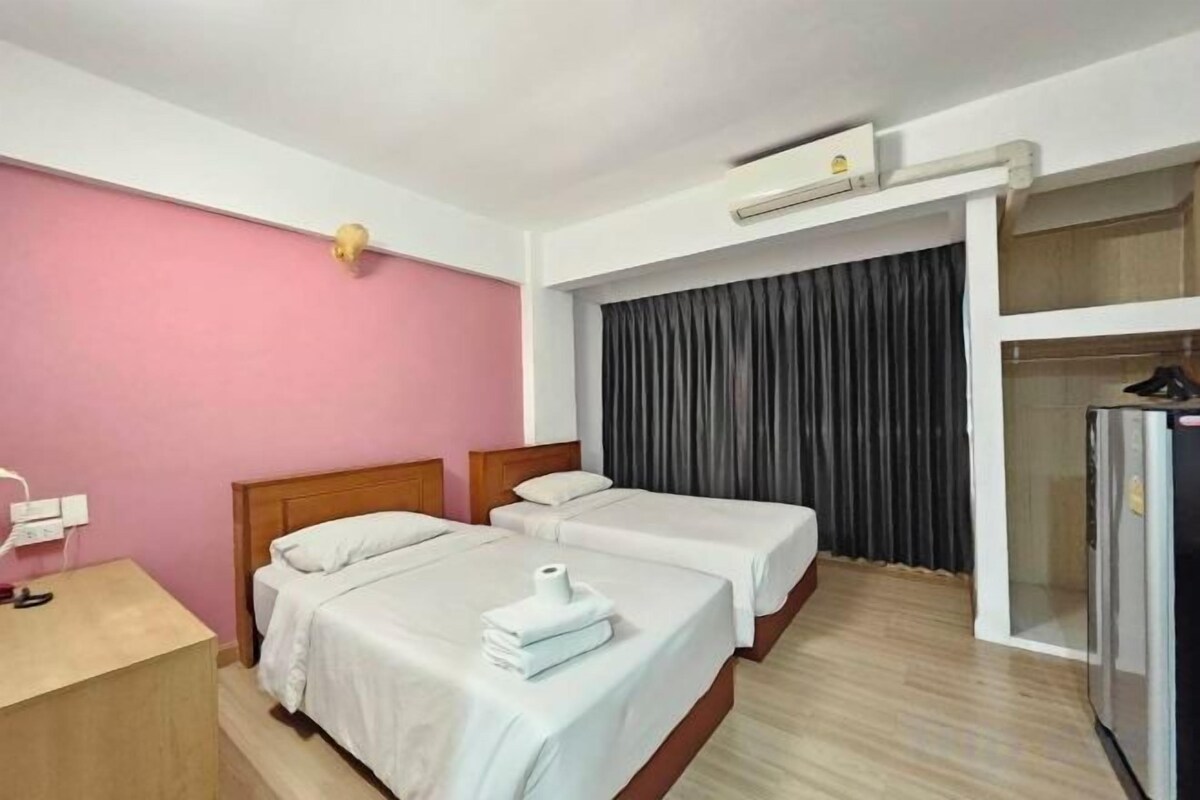 A hotel room with two beds, a desk, a wardrobe, and a minibar.