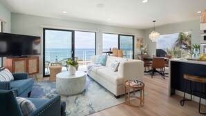 A spacious living area with a large TV, comfortable seating, a dining area, and a kitchen. - Beach View Bungalow with Stunning, Panoramic Views (Encinitas)