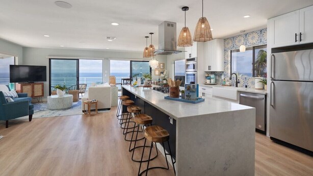 A modern kitchen with a large island, bar stools, and a view of the ocean. - Beach View Bungalow with Stunning, Panoramic Views (Encinitas)