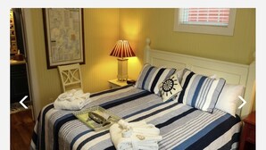 A bed with striped bedding, a pillow with a ship's wheel design, and two folded towels on the bed.