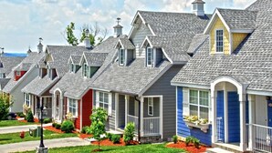 A row of townhouses with grey roofs, red and blue exteriors, and small front yards with landscaping.
