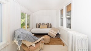 A bedroom with a bed, a chair, a window, and a radiator. - The Congamond Cottages: Private Lakefront Cottage (Suffield)