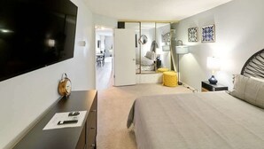 A hotel room with a bed, bedside table, lamp, and a TV mounted on the wall. - Updated Oceanfront Condo -Ground Floor- Fireplace! (Lincoln City)