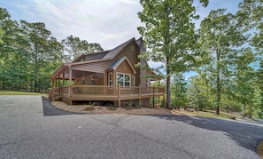 A cabin with a porch, a covered deck, and a stone foundation.