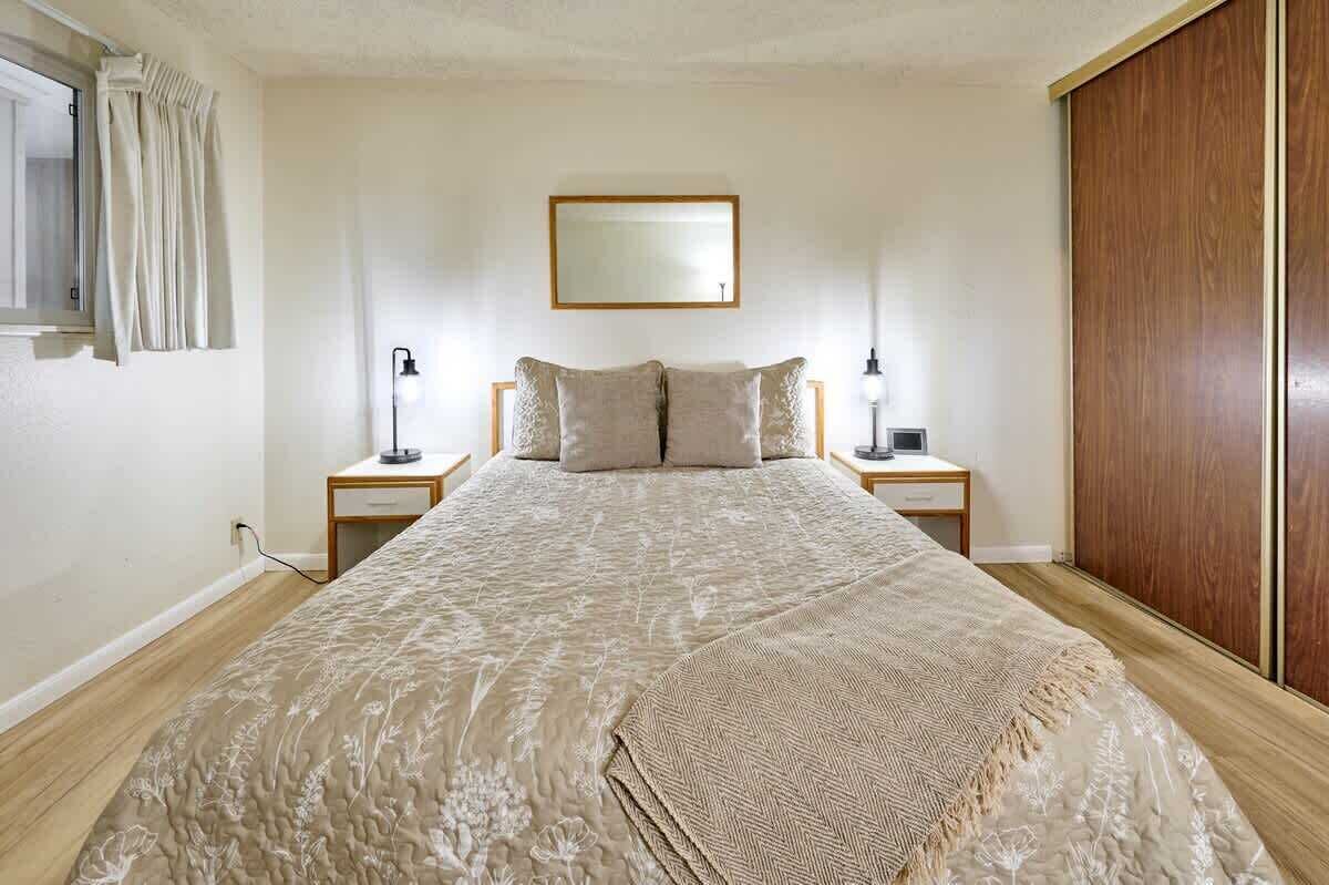 A bedroom with a bed, bedside tables, a mirror, and a wardrobe.