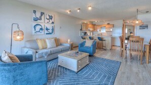 A modern living room with a sofa, armchair, coffee table, and artwork on the wall. - Ocean View Condo - Second Floor - Pet Friendly! (Lincoln City)