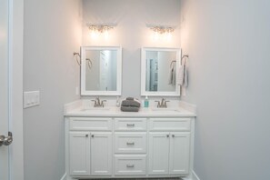 A bathroom with two sinks, a mirror above each, and a towel rack with towels. - Relax on Oak Island – Steps Away from Beach Access (Oak Island)