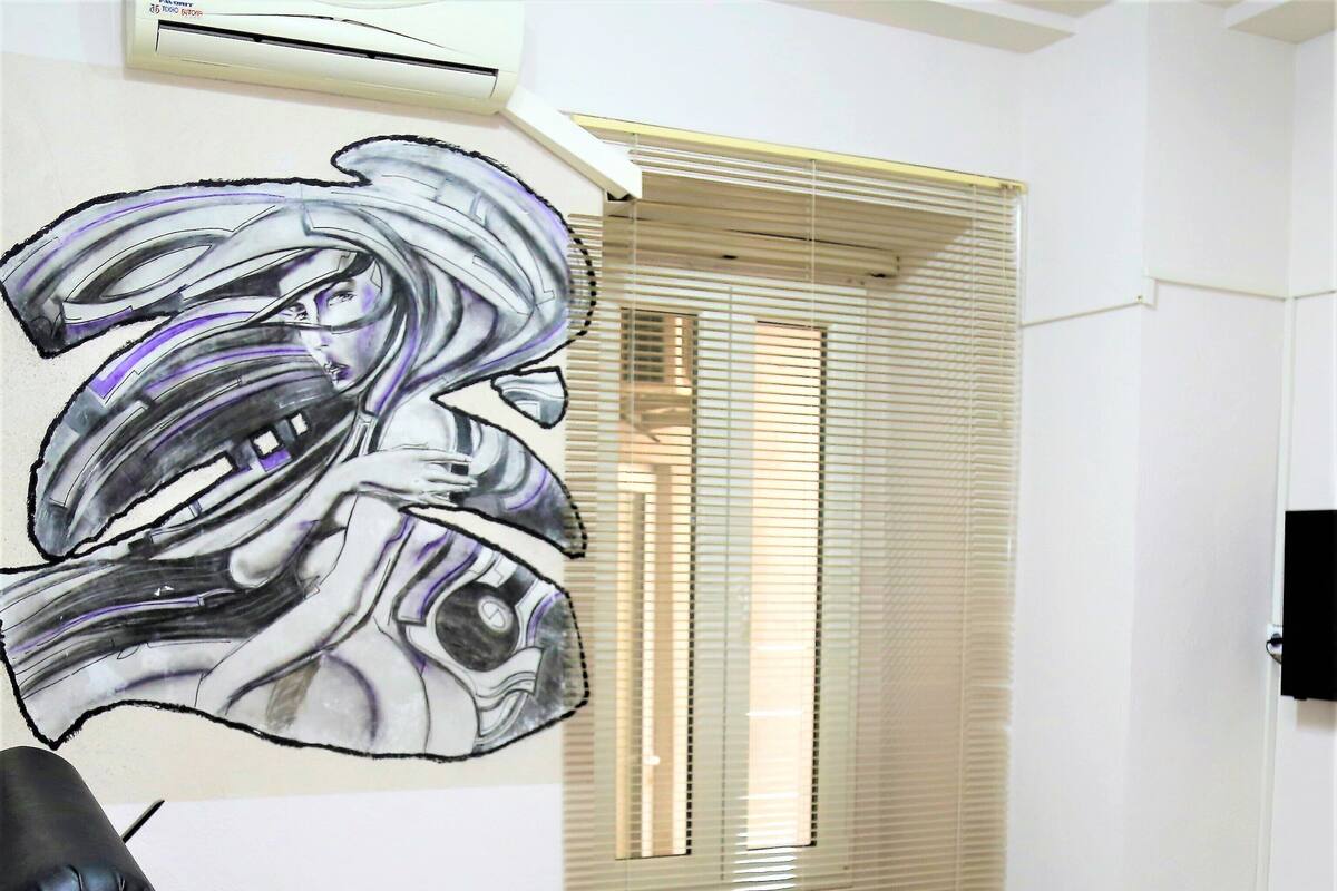 A room with a bed, a window with blinds, and a wall-mounted air conditioner.