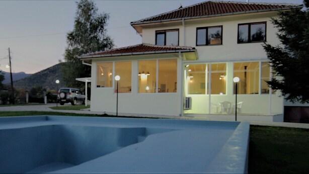 A two-story house with a swimming pool in the foreground.