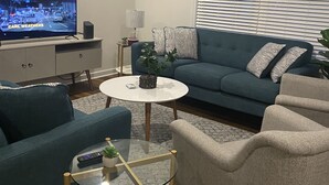 A modern living room with a TV, sofa, armchairs, and a coffee table. - Furnished 1 bedroom (Front Royal)