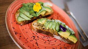 Two slices of toast with avocado and sesame seeds on a red plate.