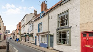 A street with buildings, including a hair salon and a red door. - 48 High Street (Bridlington)
