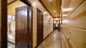 Un pasillo de madera con dos puertas, piso de baldosas e iluminación empotrada en el techo.