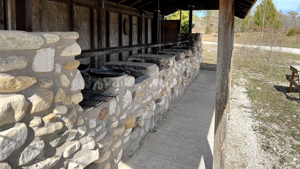 A stone wall with a grill area under a wooden shelter. - Cabin in Little Cove Adventure park, Tobermory  Cabin 14 (Tobermory)