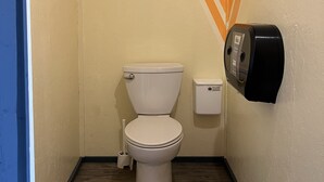 A small, compact bathroom with a white toilet, a wall-mounted paper towel dispenser, and a wooden floor. - Cabin in Little Cove Adventure park, Tobermory  Cabin 14 (Tobermory)