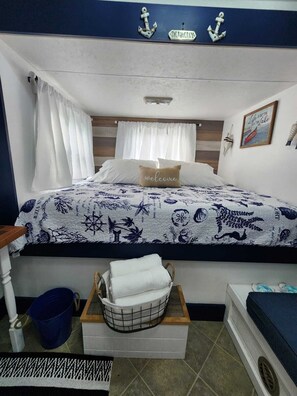 A bedroom with a nautical theme, featuring a bed with a starfish and anchor pattern, a welcome pillow, and a framed quote on the wall. - Cozy RV in Homestead, near the Everglades National Park & the Florida Keys! (Homestead)
