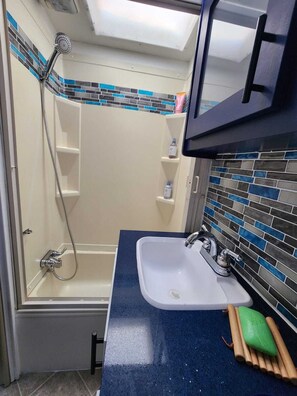 A bathroom with a shower, a sink, and a mirror. - Cozy RV in Homestead, near the Everglades National Park & the Florida Keys! (Homestead)
