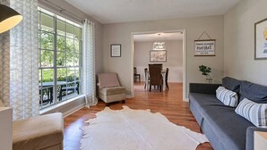 Una sala de estar acogedora con un sofá, un tapete y un comedor con una mesa y sillas.