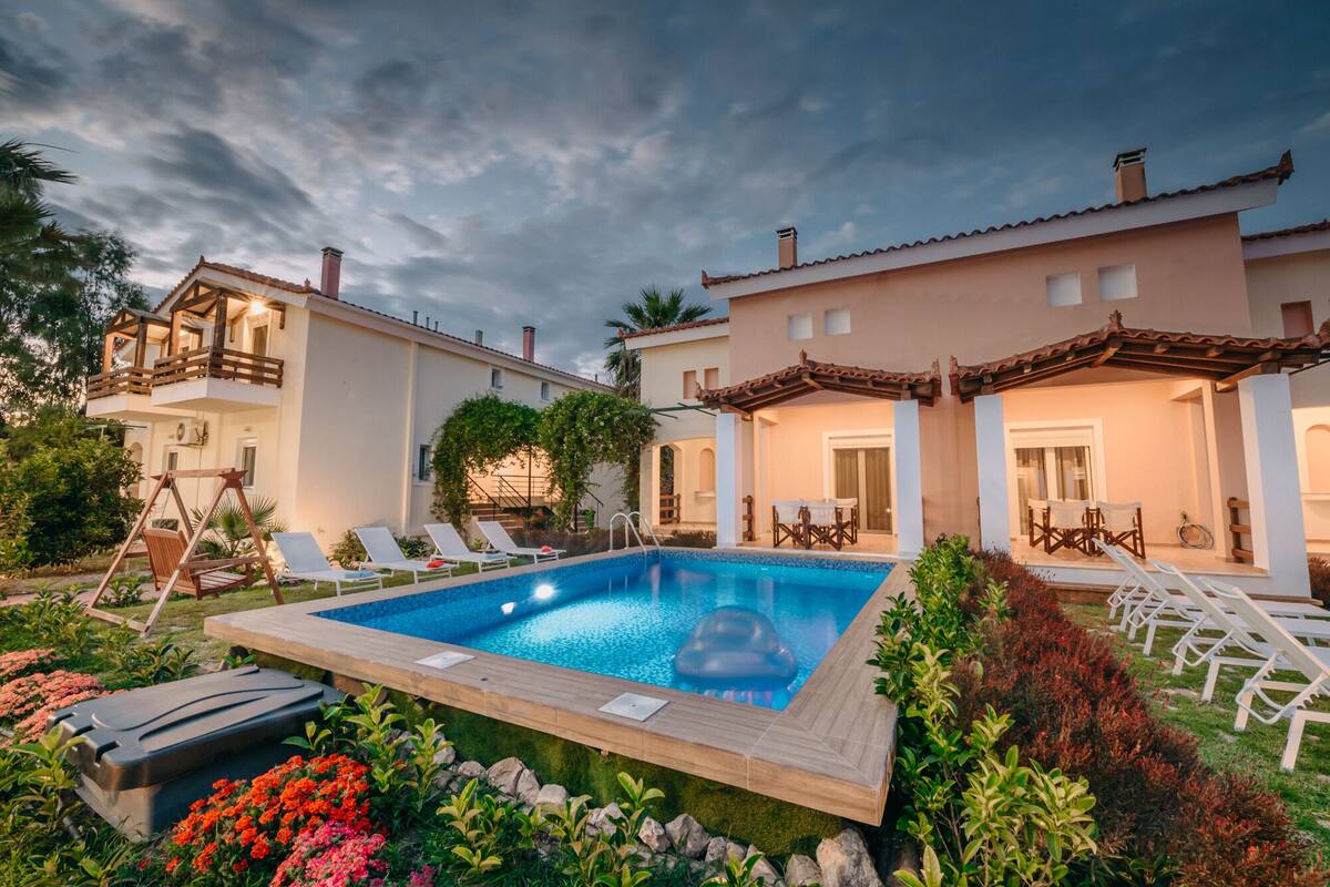 A pool area with lounge chairs, a wooden deck, and a building with a balcony.