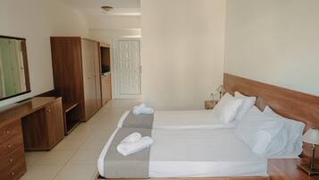 A hotel room with a large bed, wooden wardrobe, a desk, and a television.