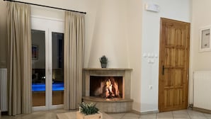Un soggiorno con camino, un tavolo in legno e una porta scorrevole in vetro che dà su una zona piscina.