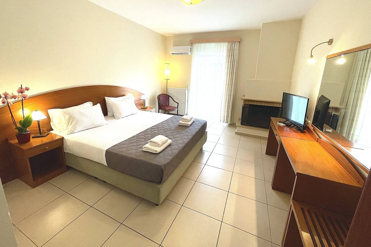 A hotel room with a bed, a desk, a television, and a window with curtains.