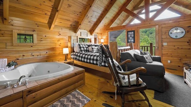 Un interno accogliente con un letto grande, una poltrona a dondolo, una vasca da bagno e un soffitto in legno.