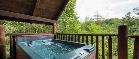 Ein Whirlpool auf einer Holzterrasse mit Blick auf eine bewaldete Landschaft.