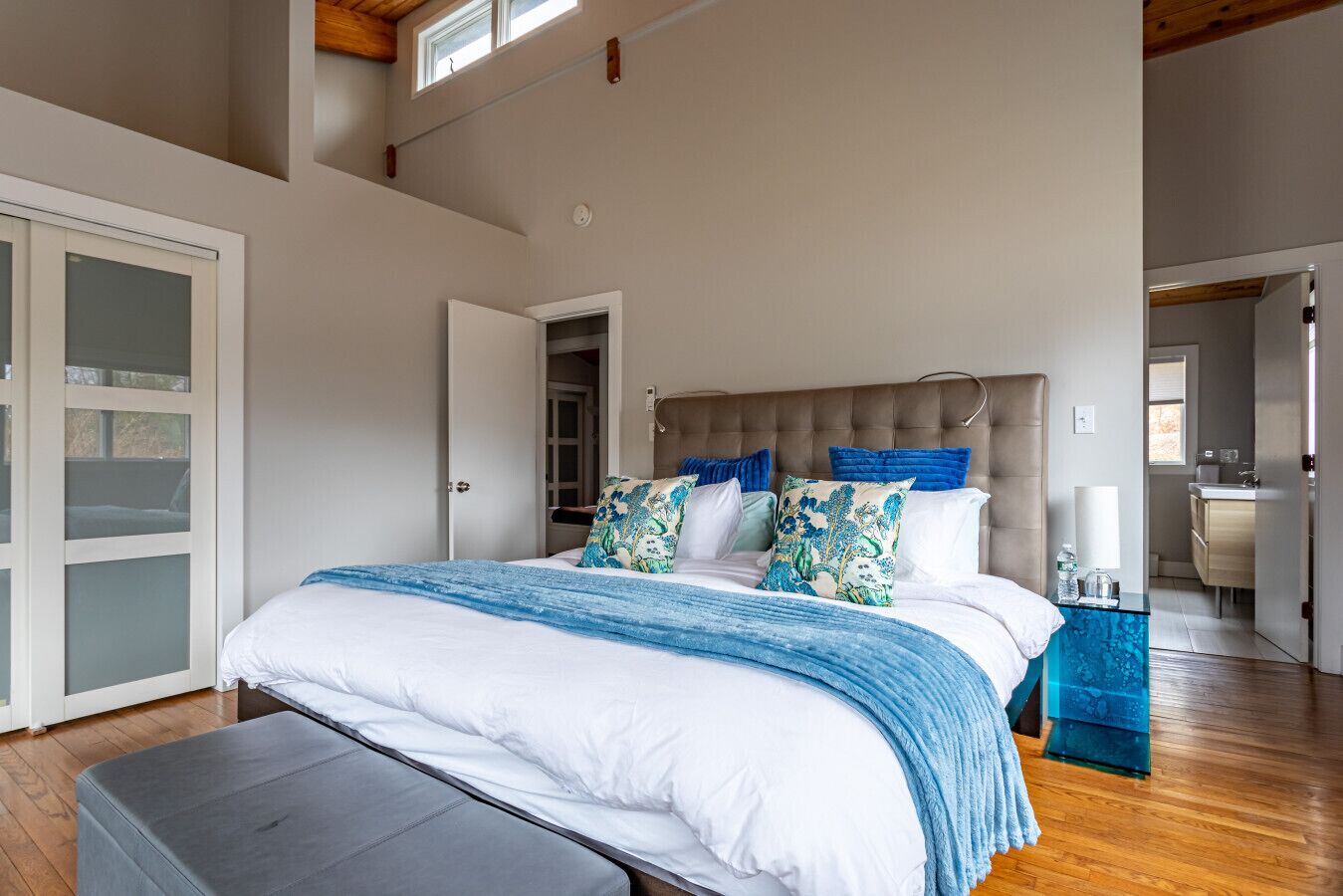 A bedroom with a large bed, a headboard, and a nightstand.