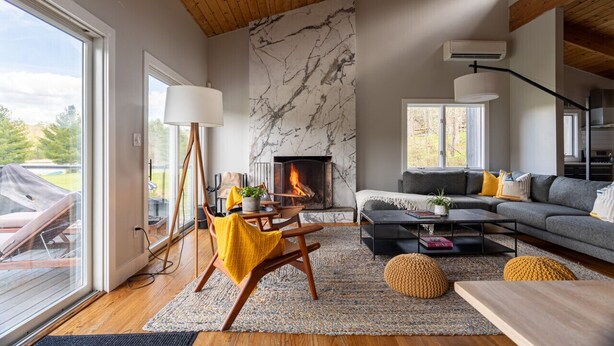 Una sala de estar moderna con chimenea, piso de madera, un sofá y un comedor.