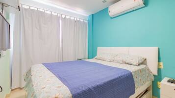 Un dormitorio con cama, mesita de noche, ventana con cortinas y aire acondicionado.