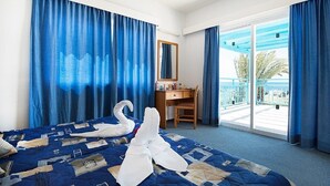 A hotel room with a bed, a desk, a chair, a balcony with a view, and a large window. - Sunny Hill Hotel Apartments (Chlorakas)