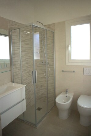 Une salle de bain moderne avec une douche à parois de verre, un bidet et des toilettes.