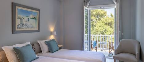 Une chambre avec deux lits, une chaise, un balcon avec une table et des chaises, et un appareil de climatisation.