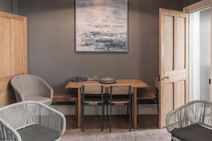 Un coin repas avec une table en bois, deux chaises, un bol et un tableau accroché au mur.
