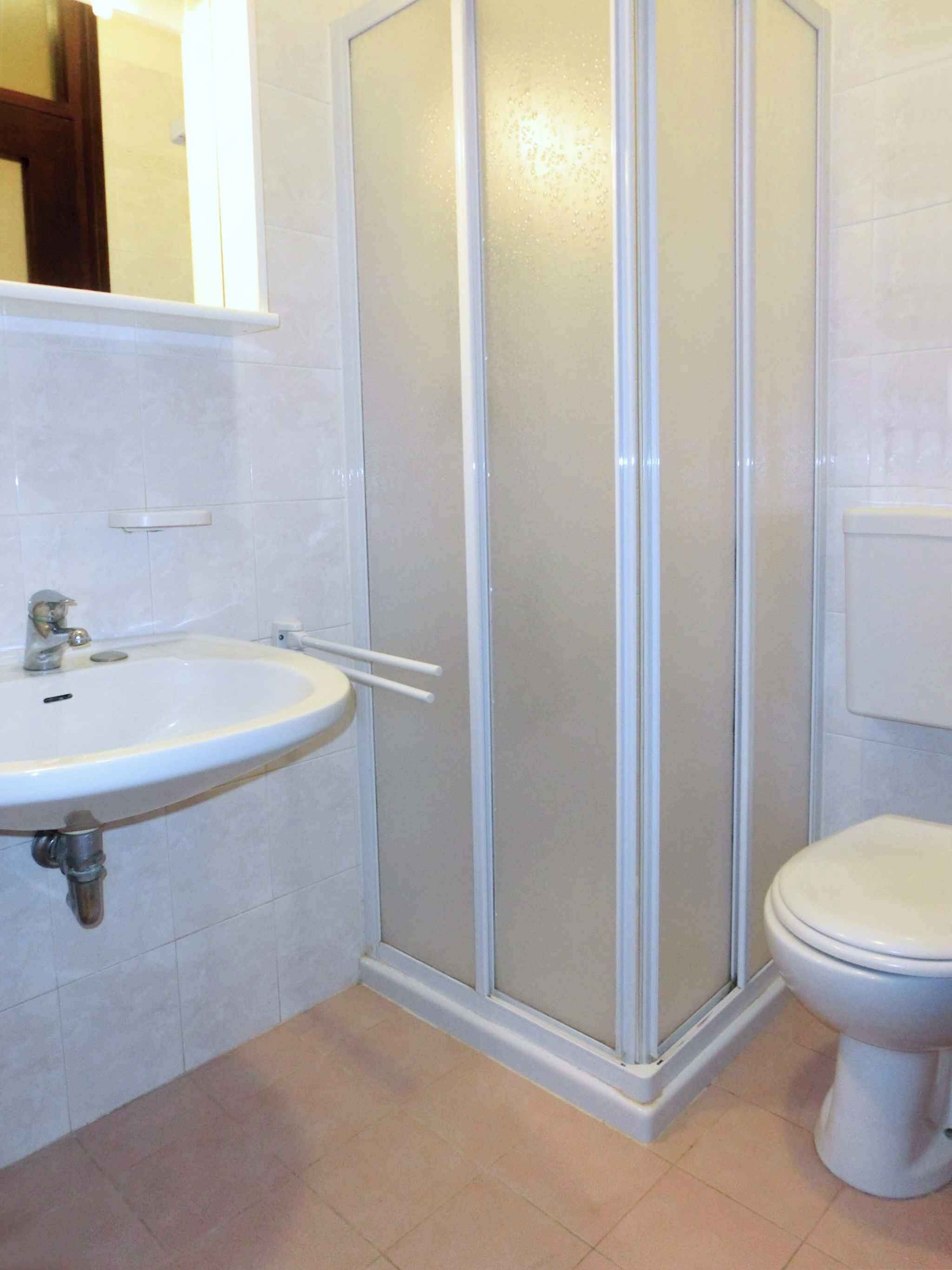 Un bany amb un rentapeus blanc, un vàter i una dutxera amb portes de vidre.