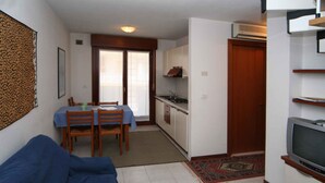 Un espace de vie compact comprenant un coin repas, une kitchenette et un téléviseur.
