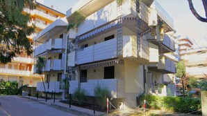 Un immeuble résidentiel à plusieurs étages, doté de balcons, d’une entrée sécurisée et surplombant un ciel dégagé.