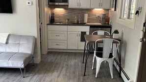 A compact kitchen with white cabinets, a microwave, and a dining area with a table and chairs. - Water's Edge Serenity On The Boulevard in Redstone (Redstone)