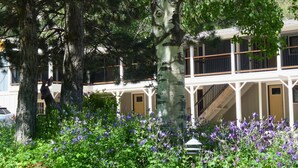 A building with a balcony and a garden with purple flowers. - Water's Edge Serenity On The Boulevard in Redstone (Redstone)