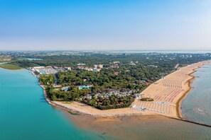 Luftaufnahme eines Küstenresorts mit Strand, einer Marina und dichter Vegetation.