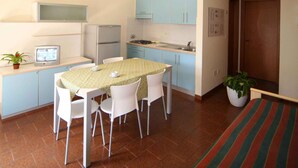 Una cocina compacta con una mesa y sillas, un refrigerador, una estufa y gabinetes azul claro.