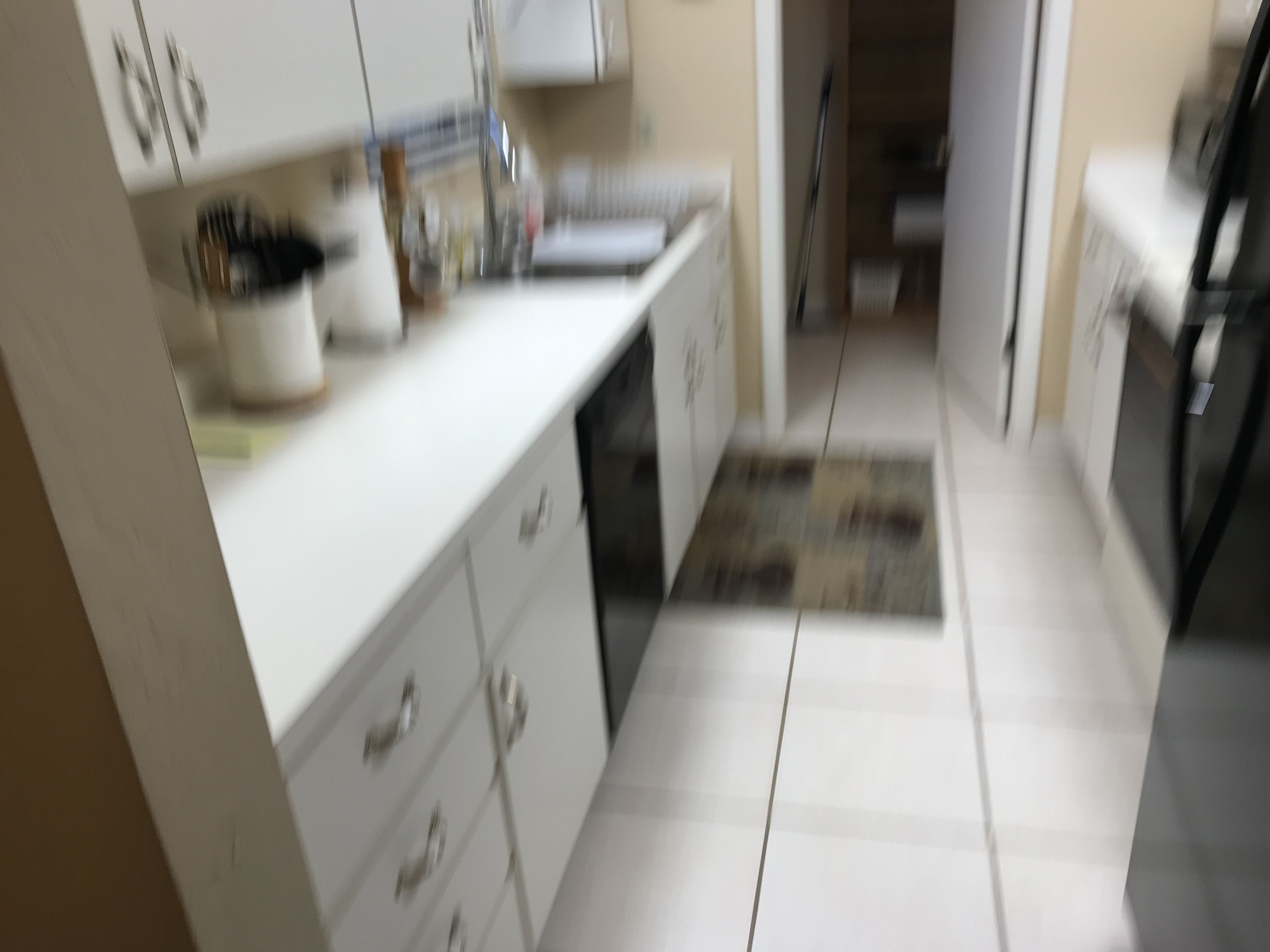 A kitchen with white cabinets, a countertop, and a tiled floor.