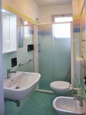 Un baño con ducha, inodoro, lavamanos y bidé.