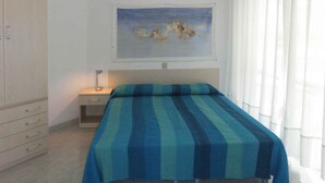 Un dormitorio con cama, mesita de noche, armario y un cuadro en la pared.