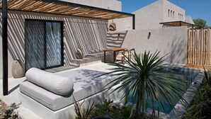 A modern outdoor living area with a pool, a sofa, and a wooden table. - Pure Villas (Sithonia)