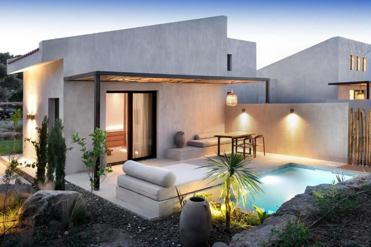 A modern house with a pool, outdoor seating, and a well-lit patio area.