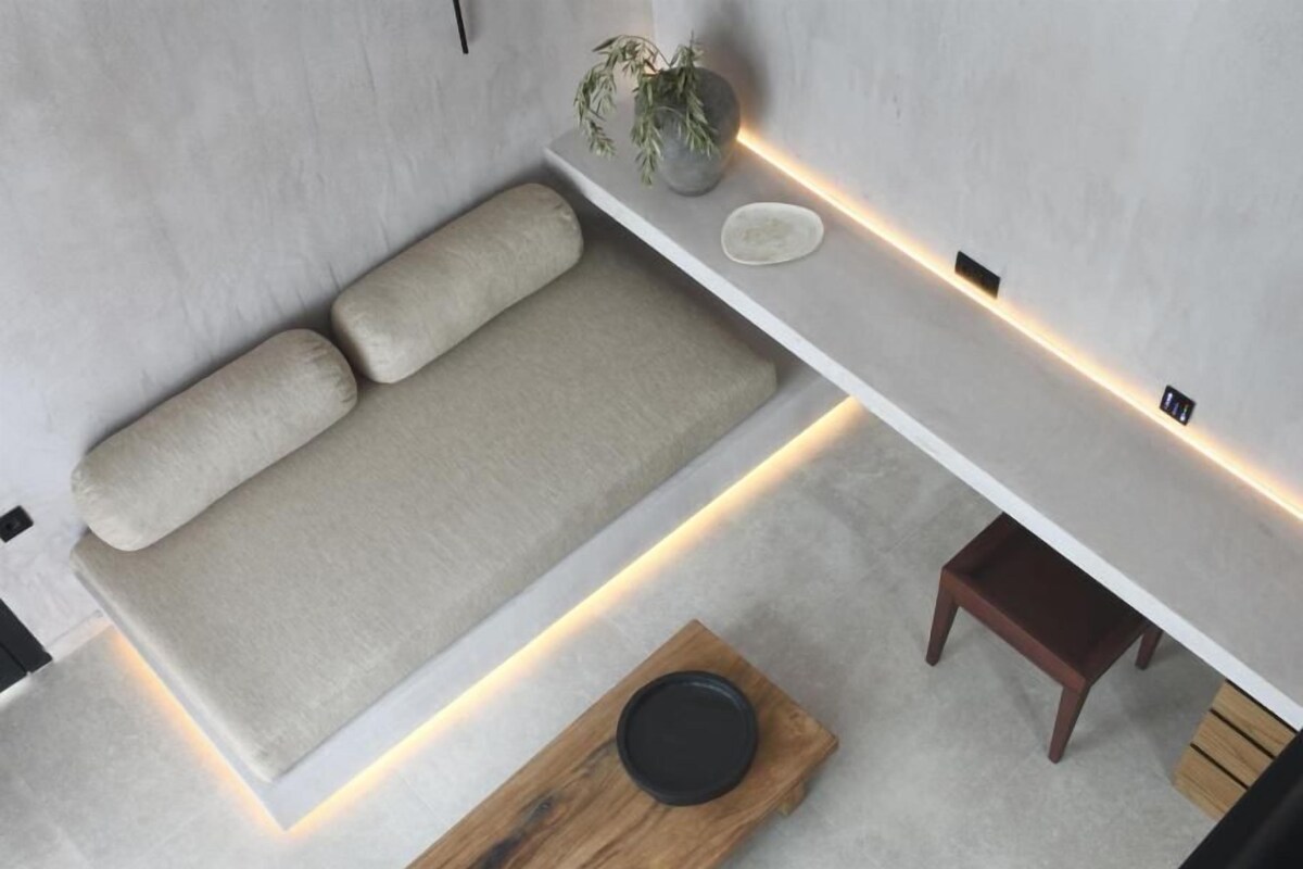 A modern room with a sofa, a wooden table, and a small shelf with a plant.