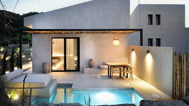 A modern house with a swimming pool, a dining area, and a large sliding glass door leading to a bedroom. - Pure Villas (Sithonia)